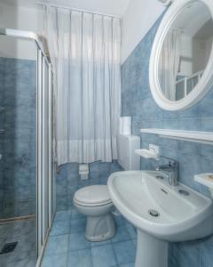 Un baño con lavabo, inodoro y espejo. en Residence La Serenissima, en Caorle
