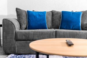 a gray couch with blue pillows and a wooden table at Chic Two Bedroom Apartment - On Street Parking Available - Netflix - Wifi - Top Rated - 311M in Birmingham