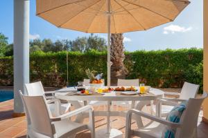 a white table and chairs with an umbrella on a patio at Villas Amarillas in Cala Blanca