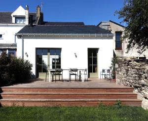 a white house with a table and chairs on a deck at Belle maison - 300m des marais - 950m de la plage in Batz-sur-Mer