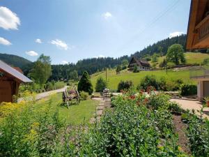 vistas a un jardín con flores y a una casa en Gästehaus Herrmann, en Bad Rippoldsau-Schapbach