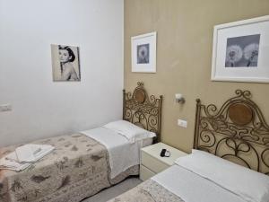 a bedroom with two beds and two pictures on the wall at Affittacamere Cecco Rooms in Ravello