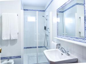 Un baño blanco con ducha y lavabo. en Hotel Ciudad del Sol, en Écija