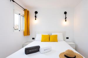 a white bed with yellow pillows and a hat on it at Happy Home by Olax Rentals in Callao Salvaje +22 photos