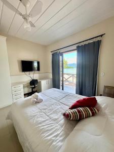 a bedroom with a large white bed with a window at Eco Sapê House in Angra dos Reis