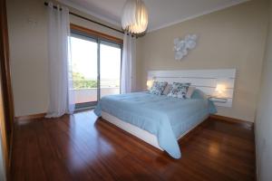 ein Schlafzimmer mit einem großen Bett und einem großen Fenster in der Unterkunft high standard rental in a quality residence with pool, tennis and view of the ocean in antas esposende 12 people in Estrada + 49 Fotos