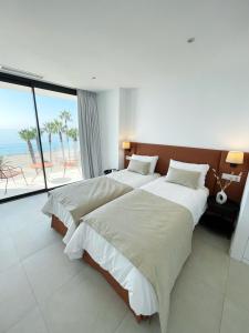 two beds in a hotel room with a view of the beach at Apartamento LaViu 1B by Croma in Estepona