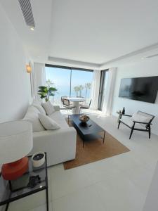 a white living room with a white couch and a table at Apartamento LaViu 1B by Croma in Estepona +8 photos