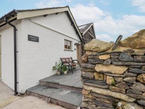 Un muro de piedra al lado de un edificio con un cartel. en Old Howgate Barn, en Ambleside