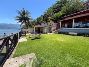 a house with a grass yard next to the water at Eco Sapê House in Angra dos Reis