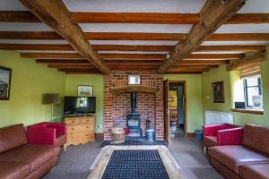 a living room with two couches and a brick fireplace at School House, cosy cottage for 12 with hot tub in the Peak District in Leek