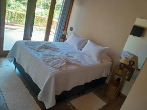 una camera da letto con un letto con lenzuola bianche e una finestra di Casa Trancoso is full-service, new house, 10 mins walk to Beach & Quadrado a Porto Seguro Altre 15 foto