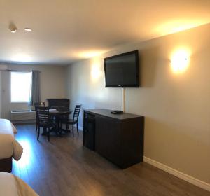 a hotel room with a television on a wall with a table at Kow's Inn in Bras D'or