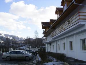 un coche estacionado al lado de un edificio en la nieve en Cabana Popasul Haiducilor, en Petroşani