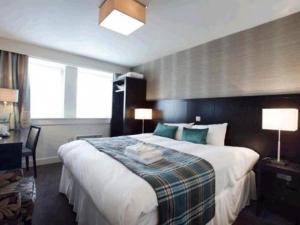 a hotel room with a large bed and a desk at The Golden Acorn Wetherspoon in Glenrothes