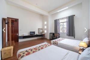a hotel room with two beds and a television at LILLY Hotel in Da Lat