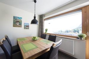 a dining room with a wooden table and a large window at Wildgrün Maxi Lodge 7 in Pfronten