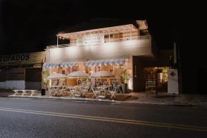 a building with tables and chairs outside at night at Sol e Mar Pousada Surf Bar in Guaratuba