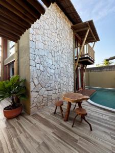a patio with a bench and a table and a pool at Malie Bangalô - Alagoas in Barra de Santo Antônio