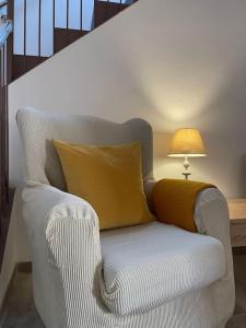 a white chair with a yellow pillow next to a lamp at Habitación Roca Foradada en Casa Camí de les Aigües Monistrol de Montserrat in Monistrol