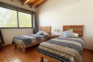 two beds in a room with a window at Casa de los Angeles Encanto en Tequisquiapan 6p in Tequisquiapan