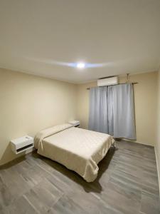 ein Schlafzimmer mit einem Bett und zwei Nachttischen und einem Fenster in der Unterkunft Mar & Luna in San Antonio Oeste