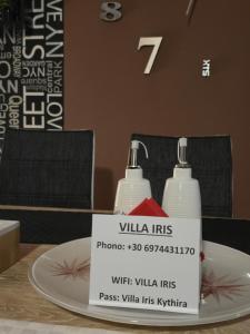 a table with a sign on a plate with two bottles at Villa Iris in Livadi