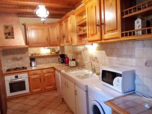 a kitchen with wooden cabinets and a white microwave at Charmante maison à la campagne près d'une ferme in Saint-Cirgues +5 photos