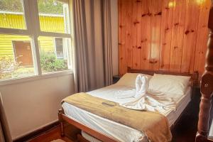a bed in a room with two windows at VELINN Pousada Casa de Campos Capivari House in Campos do Jordão
