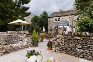 a stone building with an umbrella and a stone wall at The Lister Arms in Malham