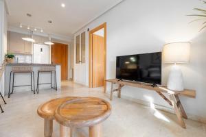 a living room with a large television and a wooden stool at Hauzify I Apartament Michelangelo in Salou +14 photos