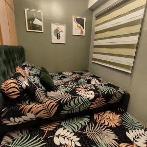 a bed with a comforter on top of it at Trees Residences Staycation in Manila