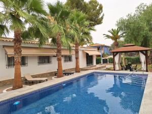 a swimming pool with palm trees next to a building at Chalet Kathia Minigolf, Ping-pong y más in Las Torres de Cotillas