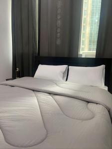 un grande letto bianco con lenzuola e cuscini bianchi di Elegant Stay Abu Dhabi City a Abu Dhabi