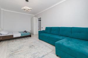 a blue couch in a living room with a bed at Красивая квартира в ЖК Комсомольский in Taldykolʼ
