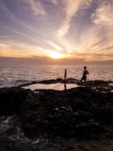 two people walking on the rocks near the ocean at Rooftop Casa El Banco in El Charco