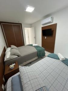 ein Hotelzimmer mit zwei Betten und einem Fernseher in der Unterkunft MANDAI - Cabo Frio - RJ in Cabo Frio