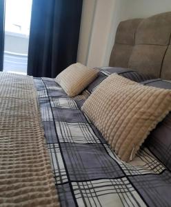 una cama con dos almohadas encima en Pupin-Apartman7, en Novi Sad