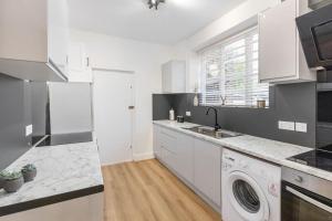 a white kitchen with a sink and a washing machine at Cozy and spacious full size flat in London