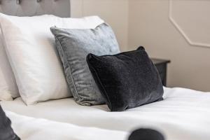 a black pillow sitting on a bed with white pillows at Cozy and spacious full size flat in London