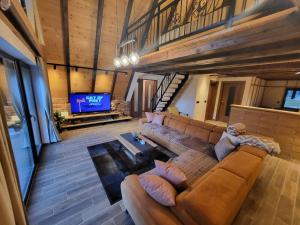 a living room with a brown couch and a tv at Jahorina Green Chalet in Pale