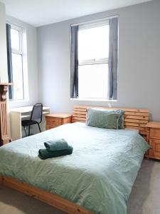 a bedroom with a bed and a desk and two windows at DB Room near NTU city Campus in Nottingham