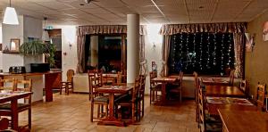 un restaurante con mesas y sillas de madera y una ventana en Hotel Les Bruyères, en L'Alpe-d'Huez