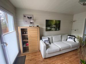a living room with a white couch and a cabinet at EIFELCOTTAGE Zaunkönig in Ulmen