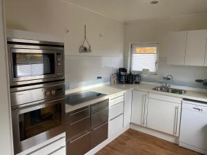 a kitchen with white cabinets and stainless steel appliances at EIFELCOTTAGE Zaunkönig in Ulmen