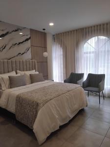 ein Schlafzimmer mit einem großen Bett und zwei Stühlen in der Unterkunft Hotel 45 Park in Sabaneta + 46 Fotos