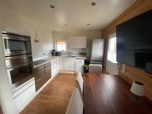 a kitchen with a wooden table and a refrigerator at EIFELCOTTAGE Zaunkönig in Ulmen +4 photos