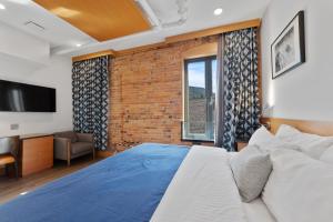 a bedroom with a large bed and a brick wall at Savoy Hotel in Nelson