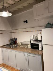 a kitchen with white cabinets and a sink and a refrigerator at La Fuente 16 Vivienda Rural in Vejer de la Frontera