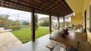 un patio con una mesa de madera y vistas a un patio en Casa c piscina a 700m da Praia de Caraguatatuba SP, en Caraguatatuba